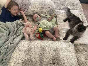 A cat and two kids laying on the bed