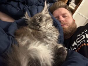 A man laying on top of a bed next to a cat.