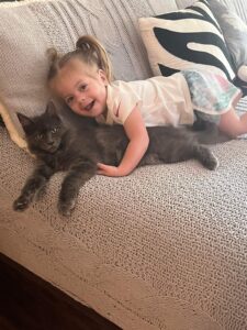 A little girl laying on the couch with her cat