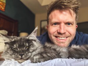 A man and his cat are laying on the bed.