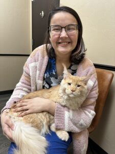 A woman holding a cat in her lap.