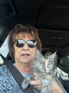 A woman holding a cat in her lap.