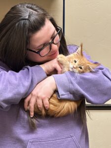 A woman holding an orange cat in her arms.