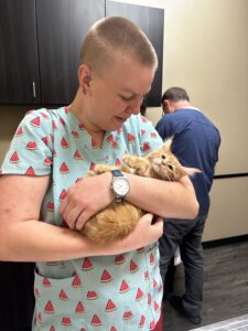 A woman holding an orange cat in her arms.