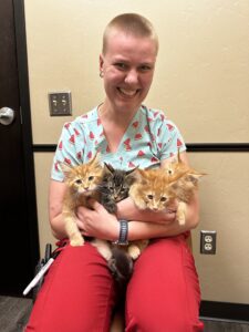 A woman holding two kittens in her arms.