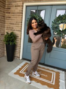 A woman holding onto her cat outside of the door.